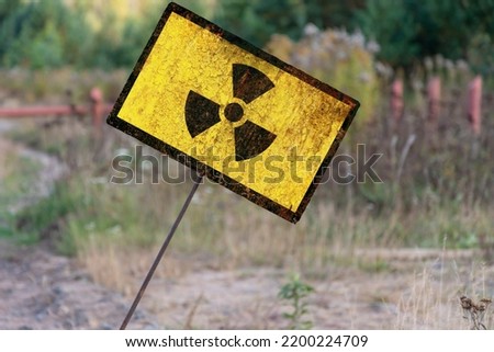 Tilted Old textural Sign of radiation hazard on the background of nature and forest, evening lighting.