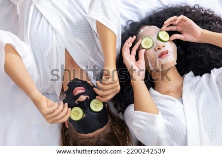 Couple of girlfriend in bathrobe doing skincare routine using facial mask and cucumber slice on spa holiday for beauty skin and treatment Royalty-Free Stock Photo #2200242539