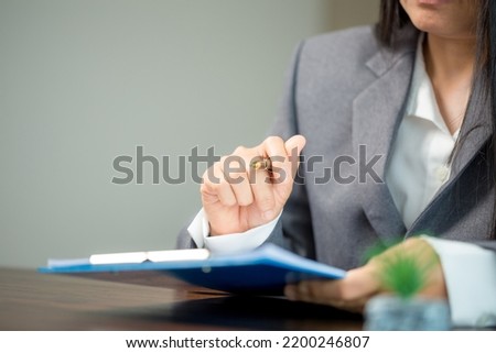 Workplace closeup person professional businesswoman sitting at desk hold pen signing or signature contract paper. Employee woman writing agreement document on paperwork form corporate at work office