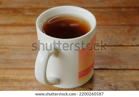 Tea in white glass on wooden table background