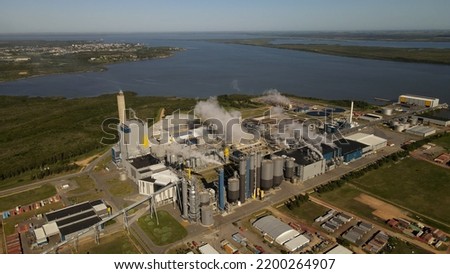Smoking chimneys in paper mill factory and surrounding landscape, Fray Bentos in Uruguay. Aerial panoramic view Royalty-Free Stock Photo #2200264907