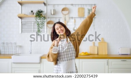 Asian young woman dancing in kitchen room. She happy and relaxing at free time on weekend Royalty-Free Stock Photo #2200275439