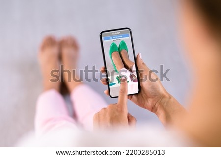 Woman Trying Virtual High Heel Shoes In Shop Or Store AR App Royalty-Free Stock Photo #2200285013