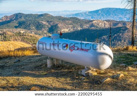 Propane flammable gas tank with mountains background on a sunny day. A no smoking sign is printed on the tank seen in the outdoors of Mount Lemmon Arizona.