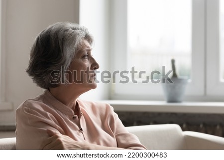 Concerned anxious senior 60s woman looking away, sitting on couch at home, thinking over problems, feeling depressed, worried, frustrated, facing loneliness, loss, grief, disease, mental disorder Royalty-Free Stock Photo #2200300483