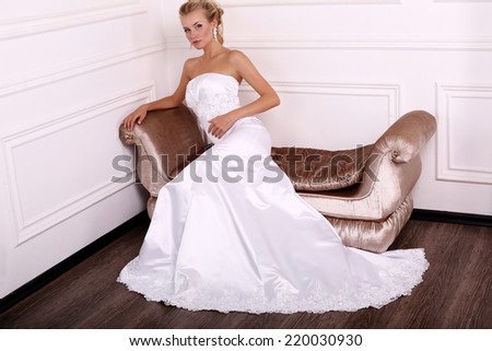 fashion photo of beautiful bride with blond hair in elegant wedding dress posing at studio