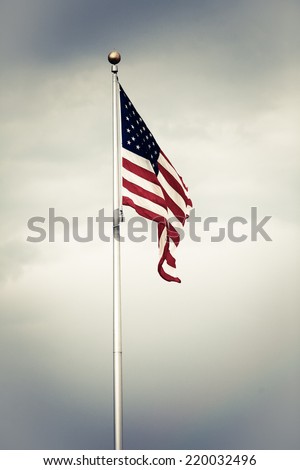 Color picture of the U.S. flag against a cloudy sky.