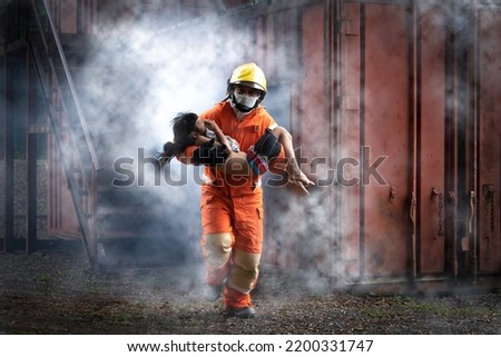 Firefighter man help Asian little girl from out container with smoke from fire.Firefighter rescue team training help people from fire accident simulation. Royalty-Free Stock Photo #2200331747