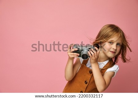 Beautiful smiling child (kid, girl) holding a instant camera. Learn photography and advertisement concept