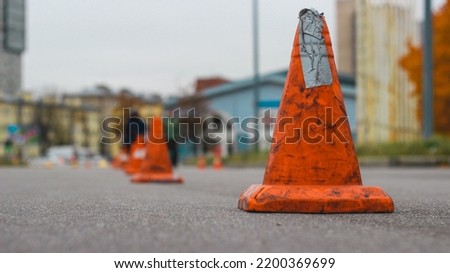 Bright orange traffic cones standing in a row on the dark asphalt. Orange cones on the asphalt prohibit the passage of cars.