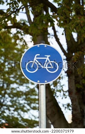 Road signs for cyclists. Bike visible on blue sign. Nature out of focus visible in the background. Environmentally conscious mobility.                            