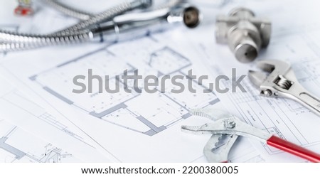 Plumbing project in house.Drawing,diagrams,plan of water supply of apartment,building.Man repairer making repairs at home.Devices,accessories, hose,tap,adjustable wrench,pressure reducer,tape measure. Royalty-Free Stock Photo #2200380005