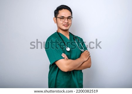 Professional good-looking asian doctor, medical worker in glasses and scrubs, cross arms and smiling, isolated over white background