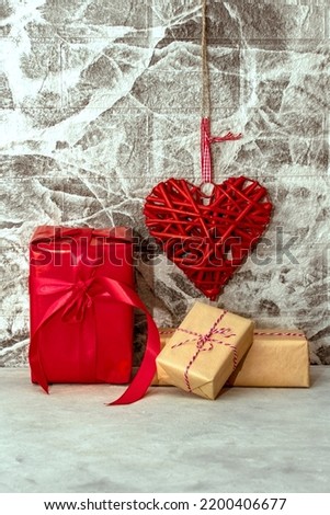 Red heart and gift box on grey wall background. Rattan work of heart shape