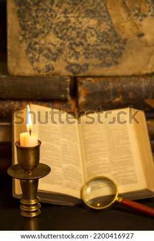 old books on the table, reading by candlelight, magnifier