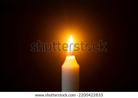 white burning candle on a black background Royalty-Free Stock Photo #2200422833