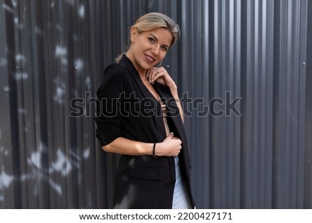 middle-aged woman looking at the camera with a smile on the background of a gray embossed wall