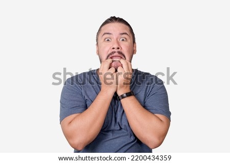 A shocked man panics, pulling on his mouth with his fingers. Scared at screwing up at his job or personal affairs. Isolated on a white background. Royalty-Free Stock Photo #2200434359