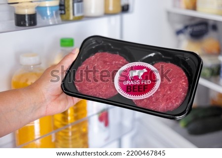 Woman holding package of grass fed beef hamburger meat Royalty-Free Stock Photo #2200467845