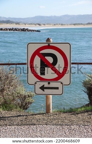 NO PARKING SIGN and arrow to the left on an ocean cliff in California