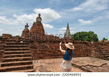 Young Asian women tourist taking photo picture with camera and traveling at Wat Chaiwatthanaram, ancient buddhist temple, famous and major tourist attraction religious of Ayutthaya Historical Park