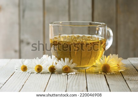 herbal tea with chamomile flowers, old wood table background