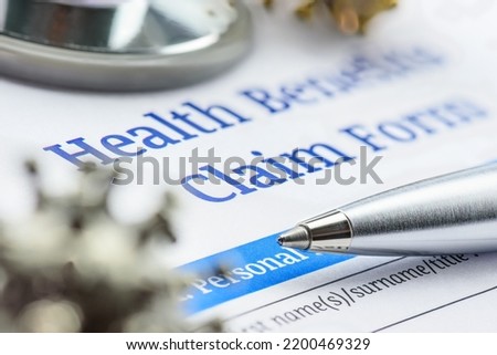 Covid-19 insurance claim, disease caused by a virus, healthcare concept : Coronavirus model on a health benefits form with a pen and a stethoscope, a patient's insurance policy will cover all costs.