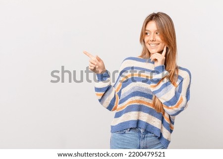 young pretty girl smiling with a happy, confident expression with hand on chin