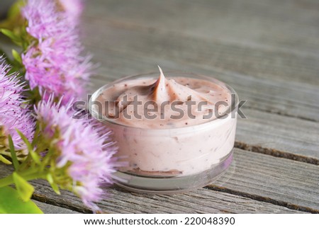 moisturizer and little pink flowers on old wood background