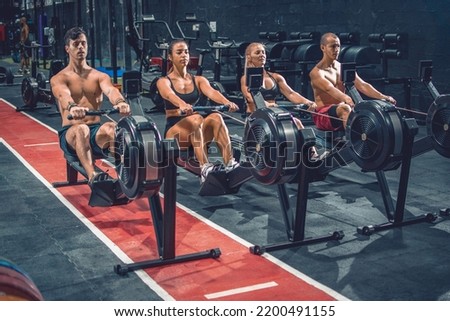 Group of sporty people working out on the rowing machines at the gym. Royalty-Free Stock Photo #2200491155