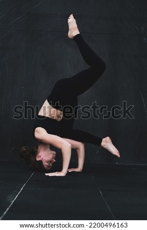 Young woman meditates, doing yoga poses and asana. Fitness girl enjoying yoga indoors. A yoga gymnast girl on a dark background. Black on Black