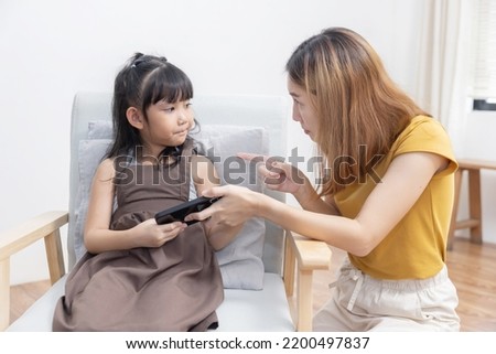 Upset Asian Mother Grab Mobile Phone From Her Kid to Stop Her Daughter From Game Addiction Royalty-Free Stock Photo #2200497837