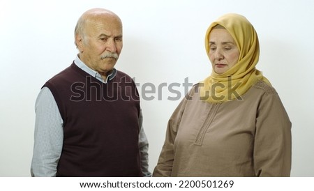 Happy old woman in hijab and her husband smiling at camera. Studio portrait of elderly husband and wife isolated on white background.