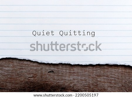 Torn paper on wood background with words QUIET QUITTING, workplace buzzword of employees  limited tasks, avoid working long hours, to set clear boundaries to improve work life balance Royalty-Free Stock Photo #2200505197