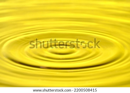 Splash drop of water with diverging water circles, on yellow background
