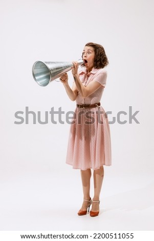 Portrait of young beautiful woman shouting expressively in megaphone isolated over white background. Big sales. Concept of beauty, retro style, fashion, elegance, 60s, 70s, family. Copy space for ad