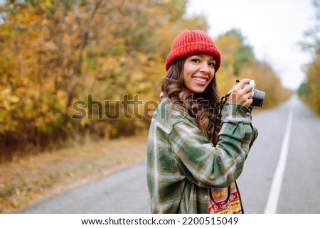 A beautiful young woman is photographed with a retro camera. Rest, relaxation, travel, lifestyle concept.