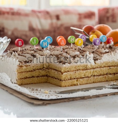 selective focus, birthday cake with letter colored inserts meaning a happy birthday. background is a blurry festive table.