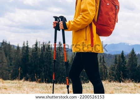 Close up Hiker with trekking poles goes against mountain landscape. Hiking and travel concept Royalty-Free Stock Photo #2200526153