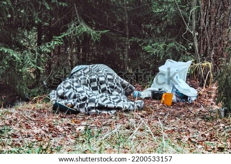 Homeless under the covers in park in winter. Social problems of poor people Royalty-Free Stock Photo #2200533157