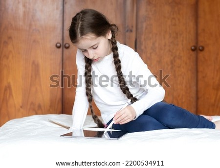 A young model draws with a pen on a tablet in a home atmosphere. Distance learning.