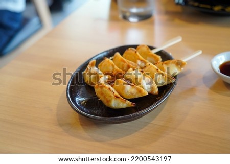 selective focus, close up Japanese dumplings is called Gyoza or Jiaozi in China, gyoza with pork meat and vegetables on black plate, dumplings snack with soy sauce.