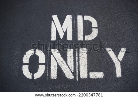 Parking spot reserved for MD. White stenciled lettering on asphalt parking spot. Taken outside a private practice, but could be outside a hospital or urgent care facility. Royalty-Free Stock Photo #2200547781
