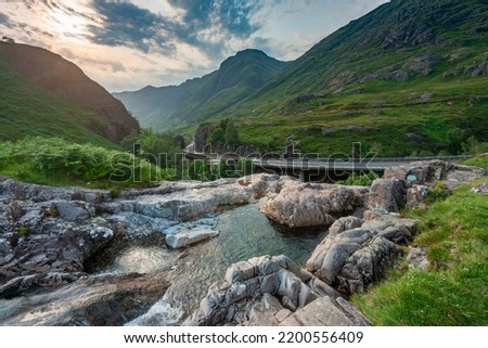 The setting sun ,over the dramatic valley of Glen Coe,in summertime,where three small rivers meet,at the foot of the Three Sisters of Glen Coe,with awesome views. Royalty-Free Stock Photo #2200556409