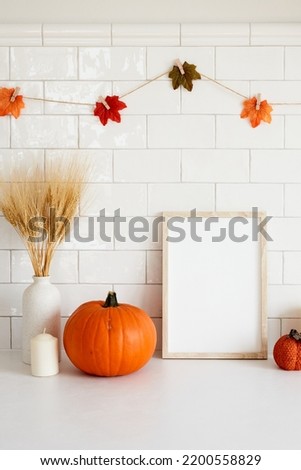 Thanksgiving frame mockup with pumpkins, vase of wheat, garland of leaves on tile wall background.