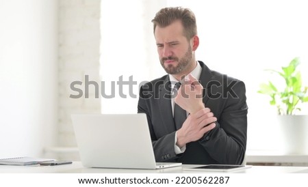 Young Businessman having Wrist Pain while using Laptop in Office
