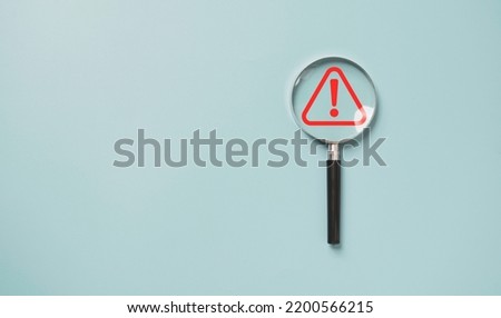 Magnifier glass with red triangle caution warning sign for notification error and maintenance concept. Royalty-Free Stock Photo #2200566215