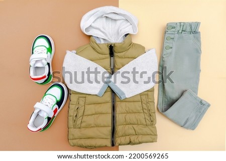 Vest,jumper,hooded sweatshirt,jeans pants with sneakers.Set of baby children's clothes,clothing,accessories for spring,autumn,winter on brown background.Fashion kids outfit.Flat lay,top view,overhead.