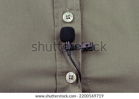 clip-on lavalier microphone is attached to women clothing close-up. Audio recording of the sound of the voice on a condenser microphone.