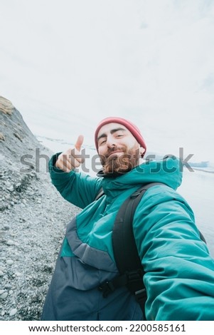 Solo male traveler on Iceland happy bout road trip new experiences. Living freedom and explore backpacking. Bearded hipster handsome guy doing the all good sign to camera taking a selfie while hiking.